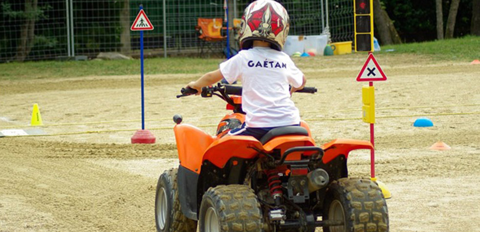 Photo d’un enfant conduisant un quad sur un terrain avec des panneaux de signalisation routière