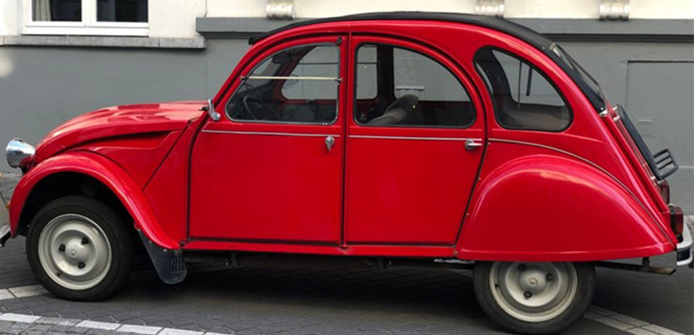 Photo d’une 2CV rouge stationnée dans une rue