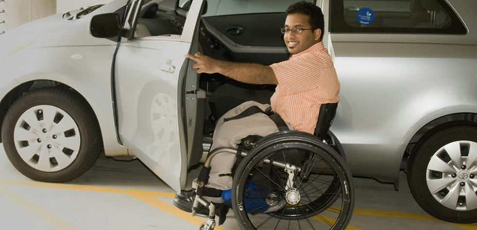 Photo d’un homme en fauteuil roulant près d’une voiture