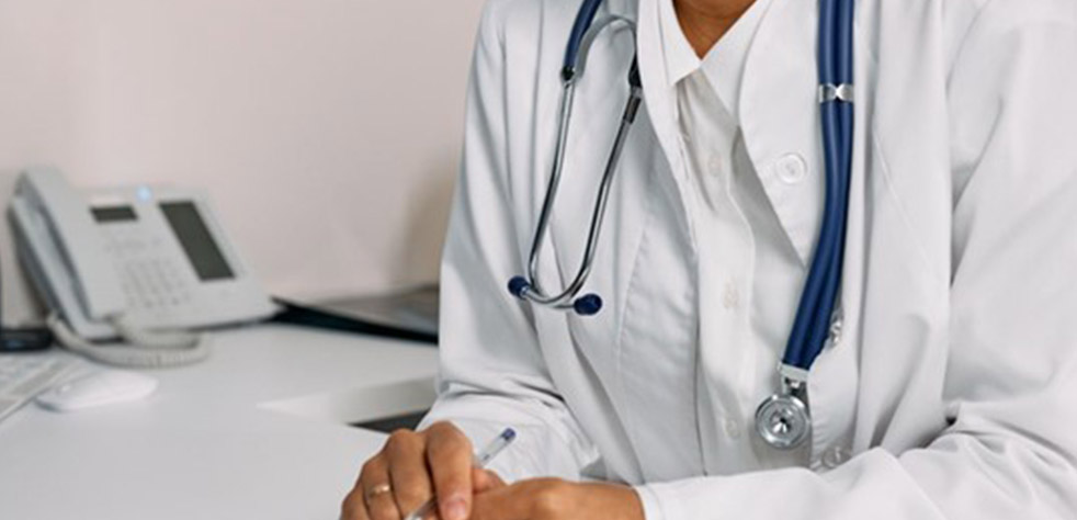 Photo d’un médecin en blouse blanche tenant un stylo avec un stéthoscope autour du cou