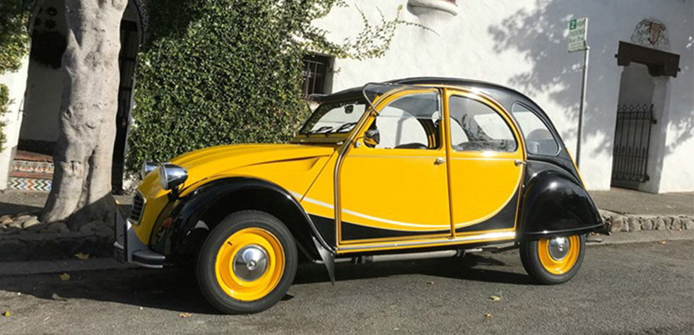 Photo d’une 2CV jaune et noire stationnée dans la rue