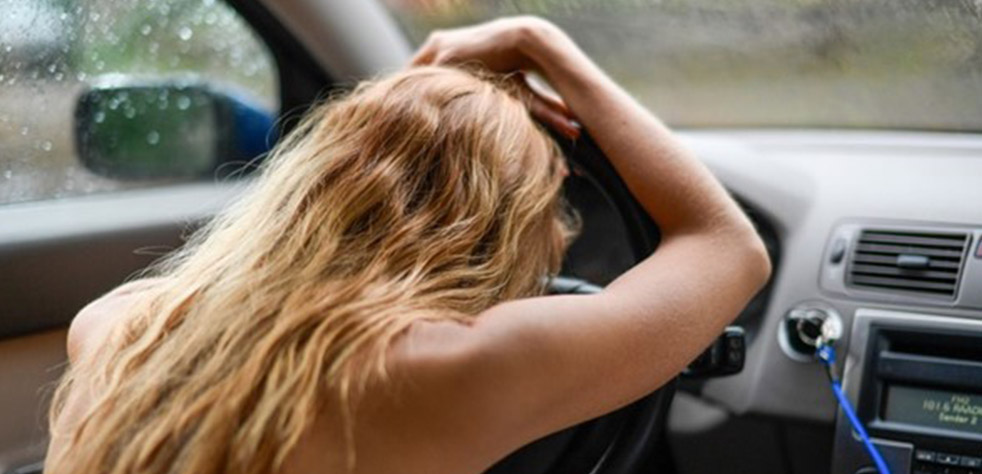 Photo d’une femme posant sa tête sur le volant d’une voiture