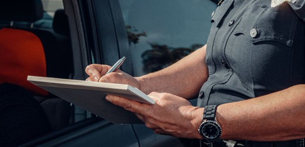 Photo d’un policier écrivant une contravention à côté d’un véhicule