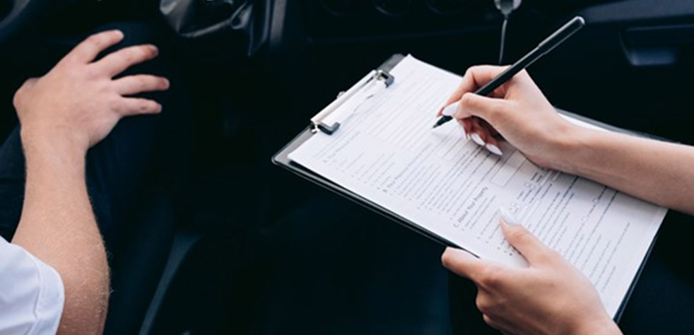 Photo d’une instructrice prenant des notes sur un document pendant un examen de conduite