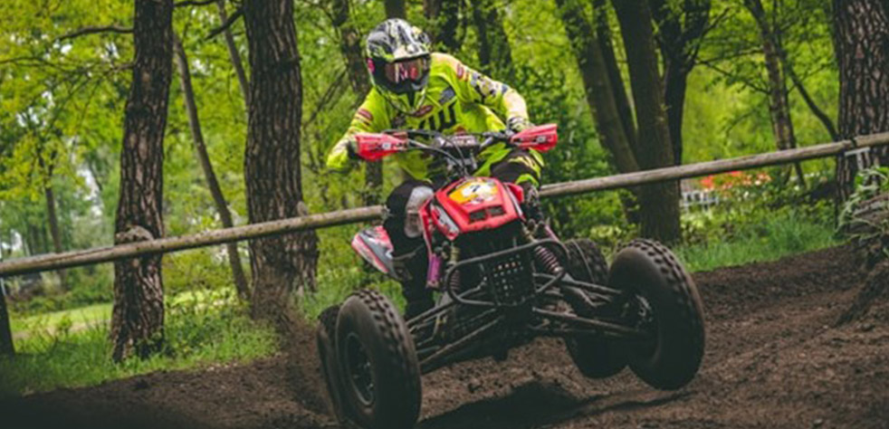 Photo d’une personne au guidon d’un quad roulant sur un circuit en terre