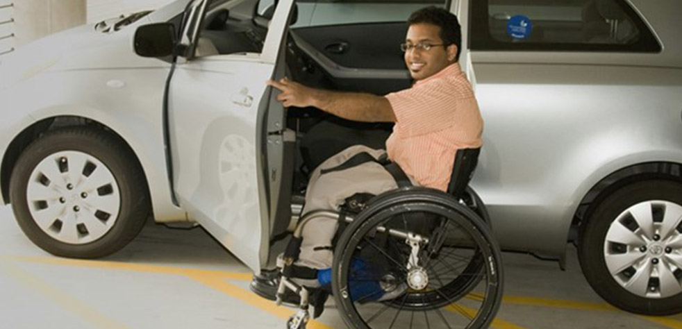 Photo d’un homme en fauteuil roulant ouvrant la portière d’une voiture