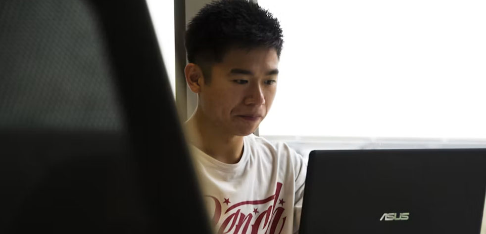 Photo d’un homme assis devant un ordinateur portable